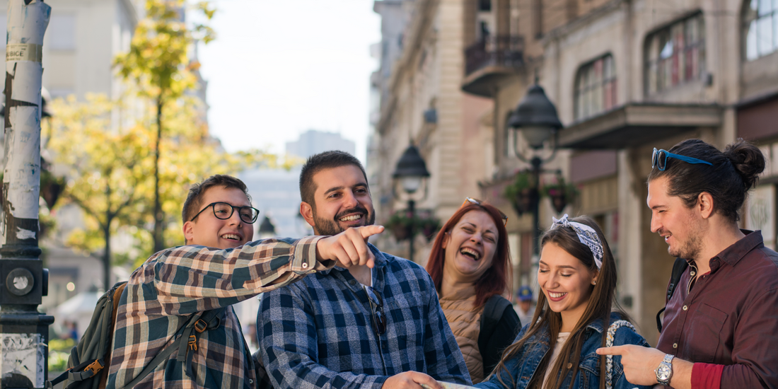 Smiling group of friends exploring a city together, enjoying sightseeing and shared travel experiences outdoors.