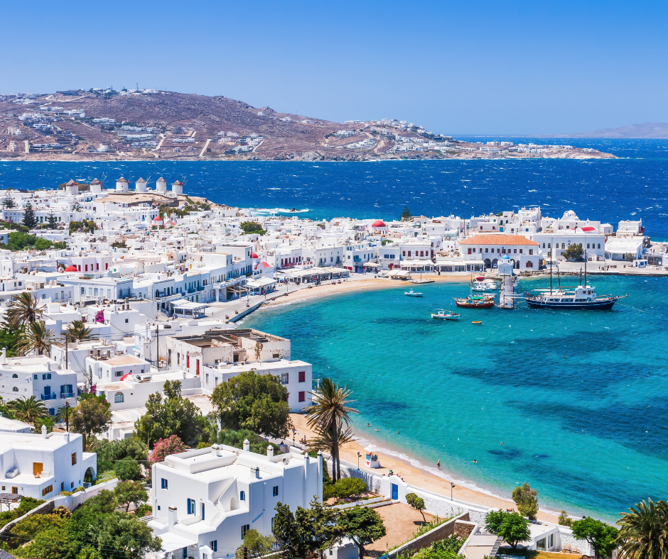 The Aegean Sea, a brilliant cerulean, reflects the azure sky above, surrounding the charming white buildings of Mykonos.