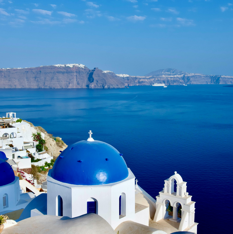 View of Oia, Santorini, at twilight, showcasing the iconic whitewashed buildings and blue-domed churches.