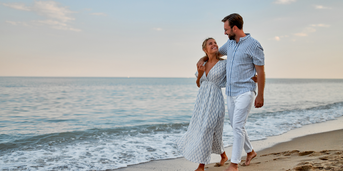 A couple strolls along the shoreline as gentle waves lap the sand.