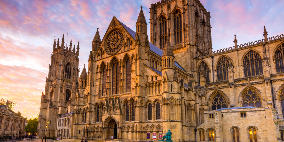 The York Minster bathed in the warm, golden light of sunrise or sunset, highlighting its intricate Gothic stonework.