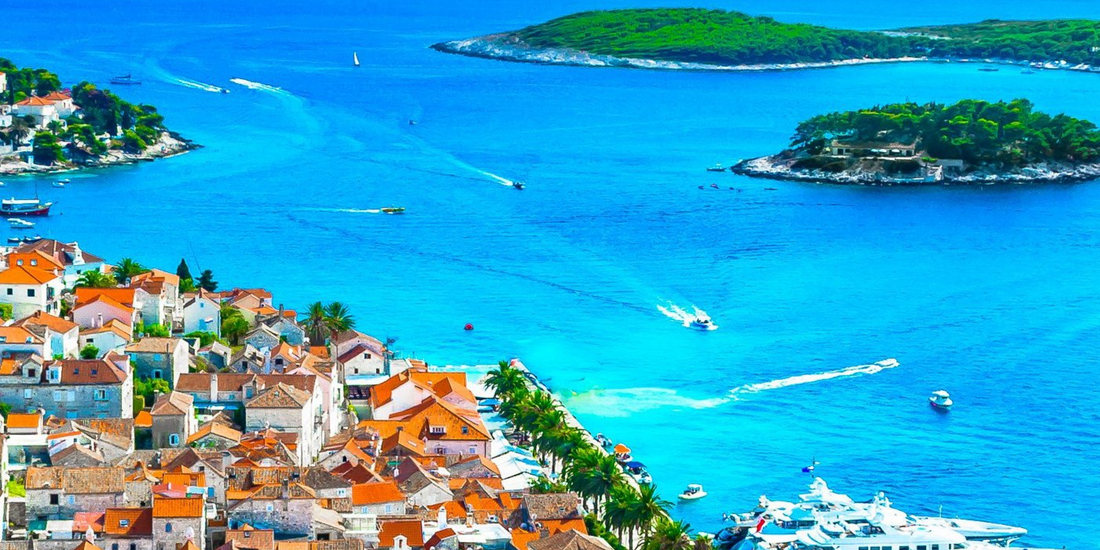 Activity on the water, showing several speedboats leaving white wakes across the bright blue sea near the harbor.