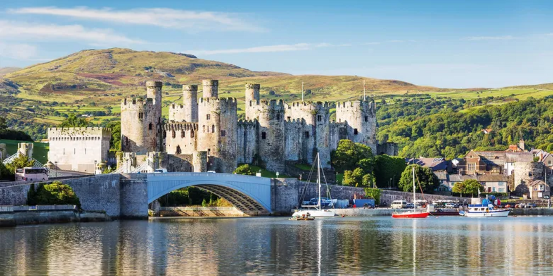 Conwy Castle, a UNESCO World Heritage Site, stands prominently against the backdrop of lush green Welsh hills.