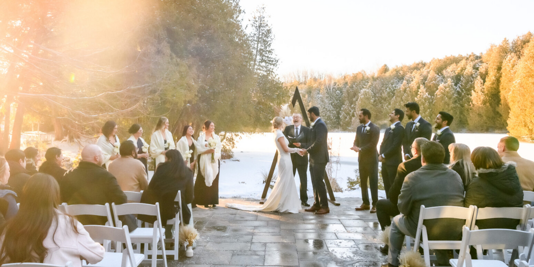 Outdoor wedding ceremony taking place on a paved area adjacent to a snow-covered landscape, featuring the bride and groom standing before an officiant.