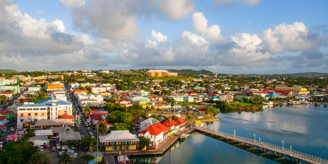Aerial view of St. John's, Antigua, showcasing the colorful buildings lining the harbor and the lush, hilly landscape backdrop.