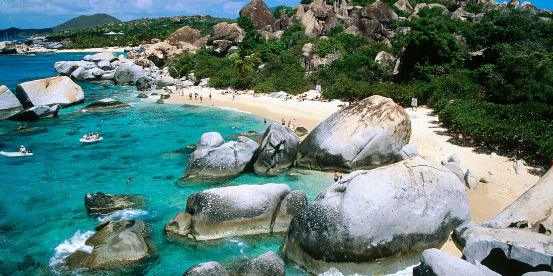 The Baths at Virgin Gorda in the British Virgin Islands featuring massive granite boulders, clear turquoise water, sandy beach coves, and lush tropical surroundings.
