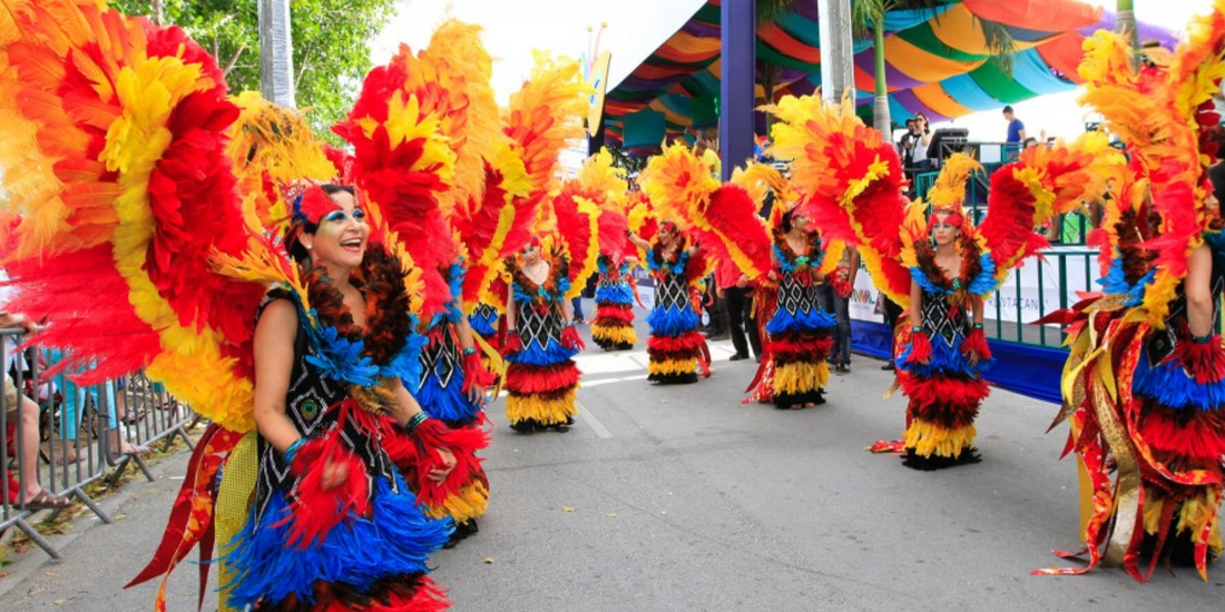 Colorful Dominican Republic carnival dancers performing in vibrant feather costumes during a cultural street festival.