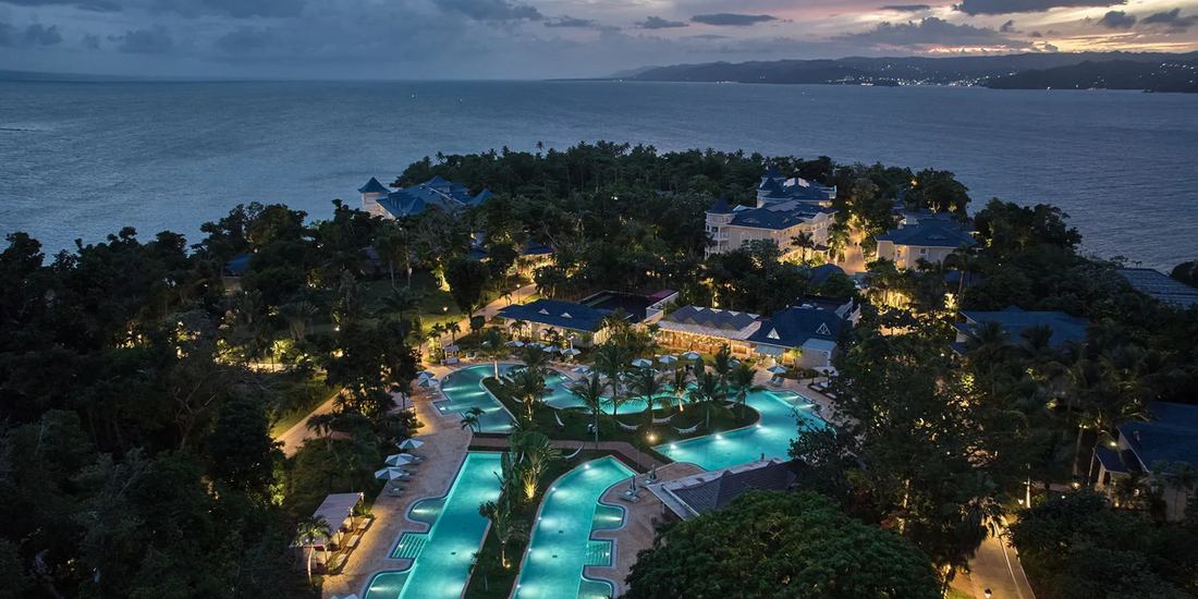 Luxury beachfront resort with illuminated pools at sunset in the Dominican Republic.