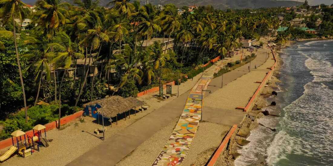Palm-lined beachfront walkway in Jacmel Haiti with colorful path beside the ocean and coastal village scenery