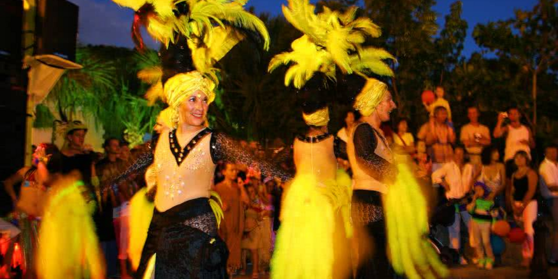 Performers in feathered costumes during a lively evening cultural celebration in Saint Barts.