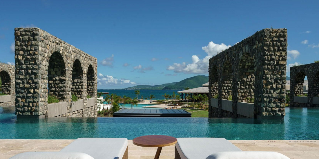 Luxury honeymoon resort pool overlooking the ocean in Saint Kitts with stone archways and mountain views