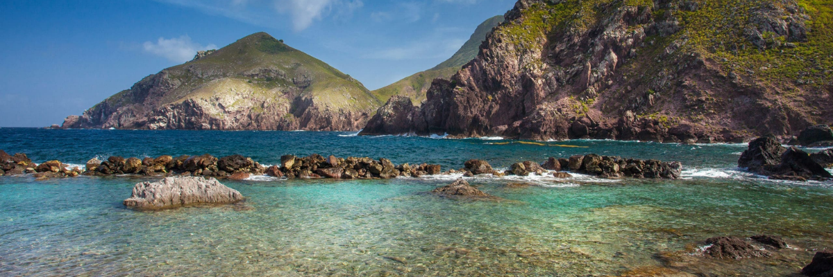Rocky coastline with crystal-clear Caribbean water and volcanic cliffs on the island of Saba.