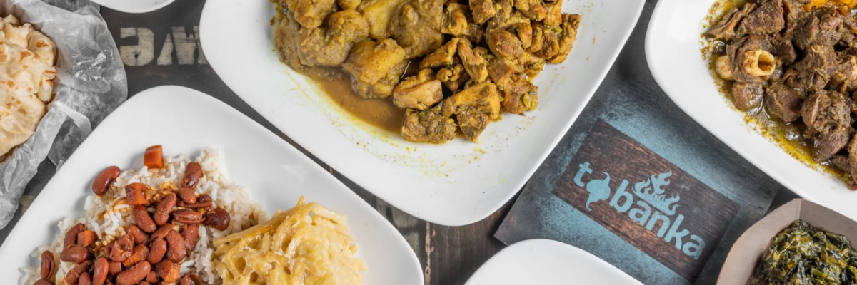 Traditional Caribbean meal featuring jerk chicken, curry chicken, rice and peas, macaroni pie, stewed meat, and local island side dishes.